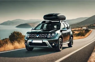 Voiture Dacia Duster équipée d'un coffre de toit noir, roulant sur une route de vacances.